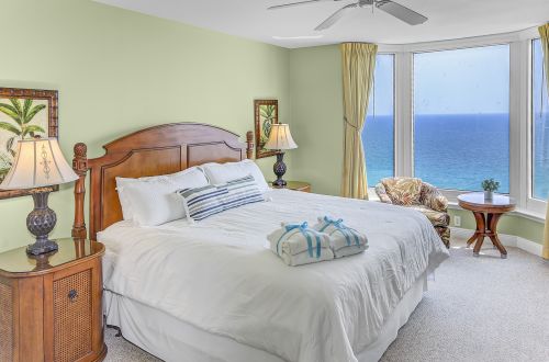 A wide-angle view of a guest room with a large bed, furniture, and an ocean view.
