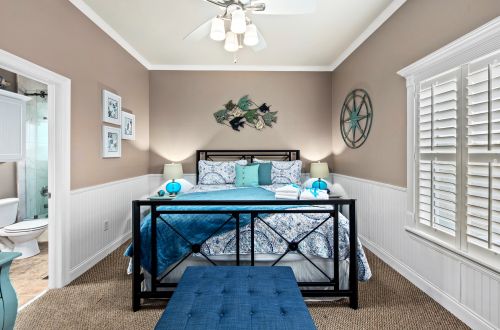 A neatly decorated bedroom with a bed, window, and ceiling fan.