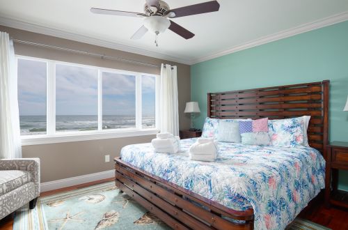 A bedroom with a large bed, window, and ocean view.