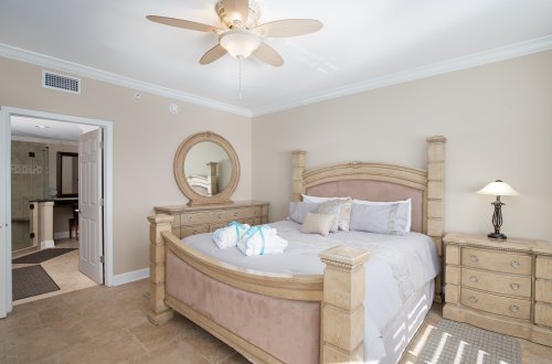 A hotel bedroom with a large bed, dresser, and nightstand.