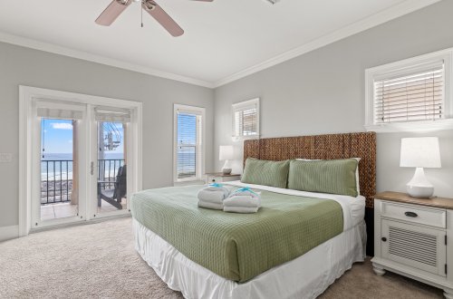 A wide-angle view of a guest room with a large bed, balcony access, and modern furnishings.