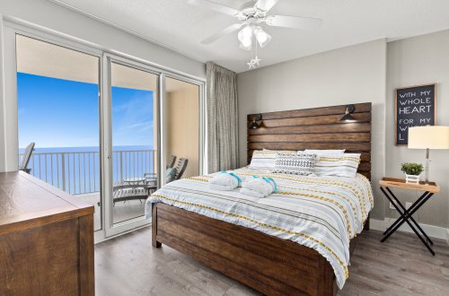 A wide room with a bed, balcony, and ocean view.