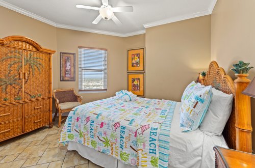 A wide-angle view of a bedroom with a beach-themed bedspread.