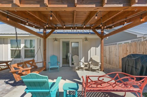 A covered outdoor patio with wooden pergola, string lights, and colorful outdoor furniture.