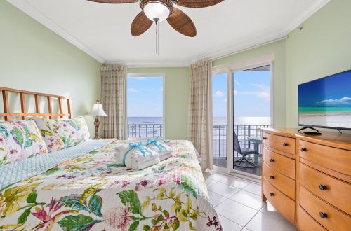 A wide-angle view of a guest room with a bed, balcony access, and ocean view.