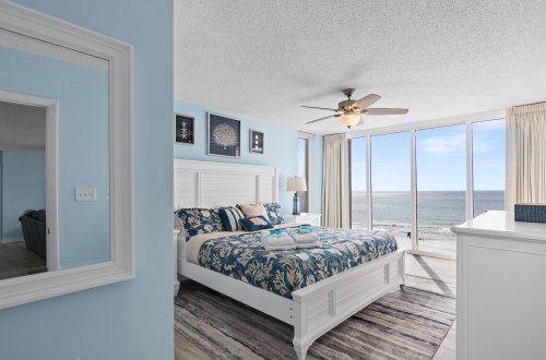 A wide view of a room with a bed, window, and ocean view.
