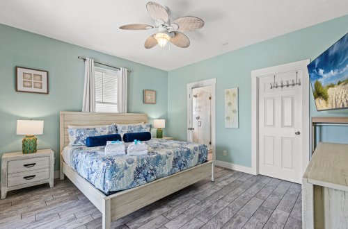 A wide-angle view of a bedroom with a bed, nightstands, and a ceiling fan.